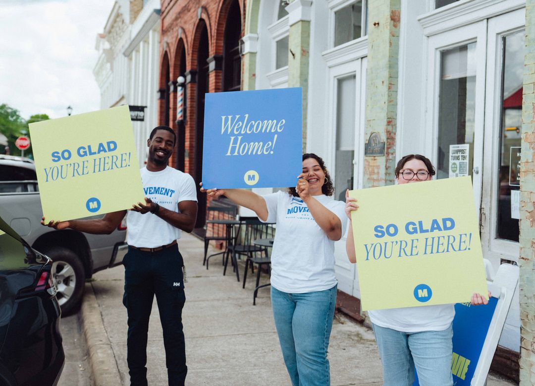 Movement Church volunteers holding Welcome Home signs
